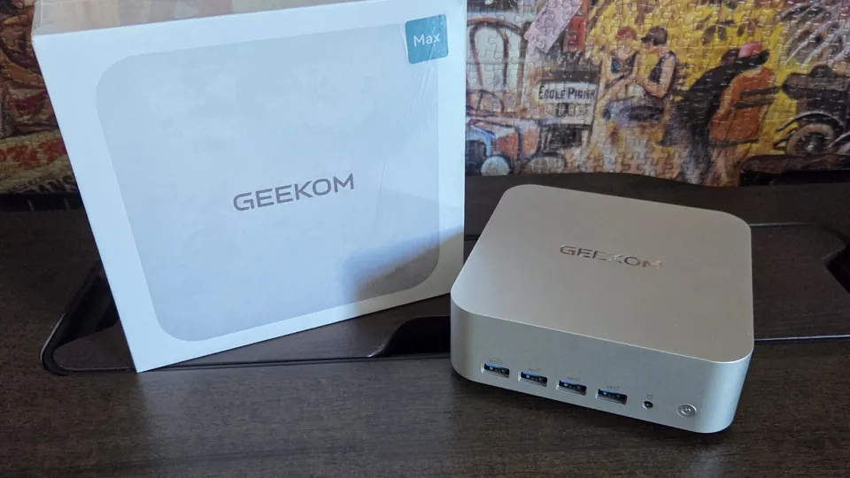 Geekom A9 Max, boîtier carré argenté posé devant sa boîte blanche