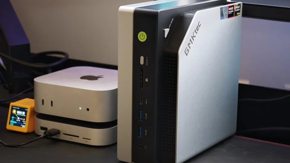 GMKtec EVO-X2, mini-PC vertical argenté à façade noire, à côté d'un Mac mini sur un bureau